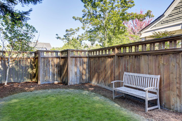 House back yard with wooden bench standing by the fence