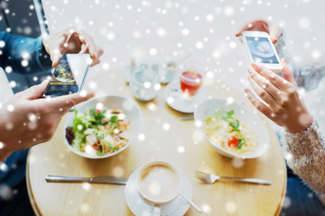 close up of couple picturing food by smartphone