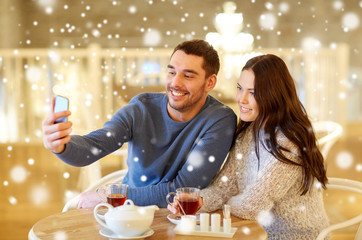 couple taking smartphone selfie at cafe restaurant