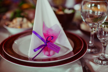 Sweets in pink pocket stand behind the serviette on the dinner p