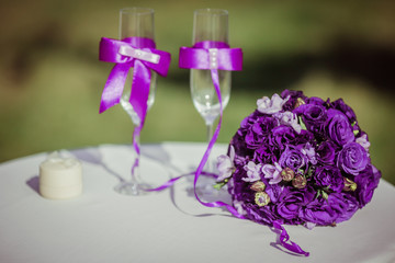 Gorgeous dark violet wedding bouquet stands behind champagne flu