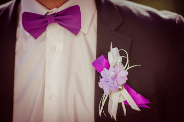 White and violet boutonniere pinned to black jacket