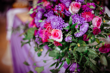 Gorgeous bouquet made of greenery and violet flowers stands on t