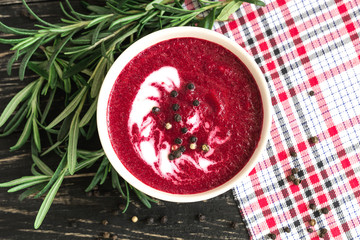 Hot cream beet soup with spices on a wooden background