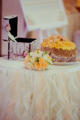 Wedding bread, peach bouquet and a chest stand on the white tabl