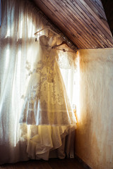 Gorgeous wedding dress illuminated with daylights hangs from the