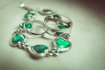 Delicate wedding rings lie over the silver necklace