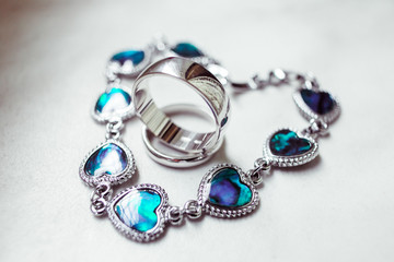 Silver bracelet made of crystal hearts lies around silver rings