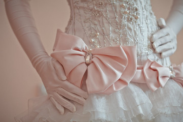 A closeup of pink bow on rich wedding dress