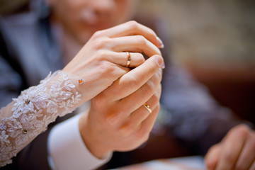 A closeup of newlyweds hands with golden rings on their fingers