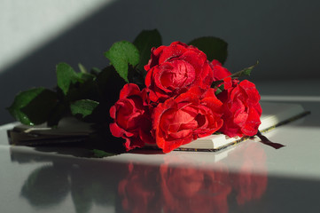 Bouquet of red roses on the notebook. Romantic still life for Valentine's day or Birthday greetings