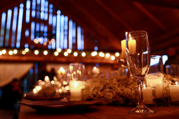 Empty glasses stand between plates and candles on the wooden tab