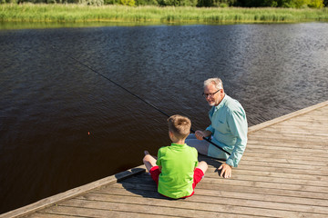 grandfather and grandson fishing on river berth