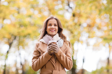 happy young woman drinking coffee in autumn park