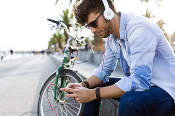 Handsome young man listening to music in the street.