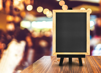 Blackboard with easel on wood table at blurred coffee shop backg