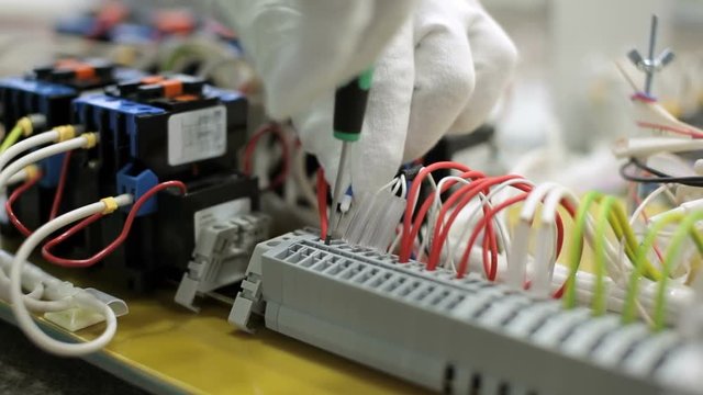 Technician in white gloves insert wire in terminal block with insertion tool