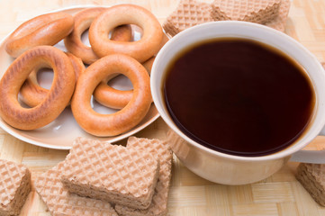A cup of black tea with bagels and wafers