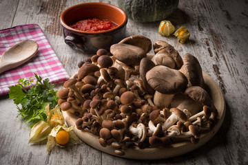 Fototapeta premium Misto di funghi freschi su un piatto tondo in legno su un tavolo 