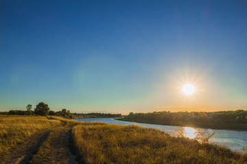 Landscape with river and dirt road to sunset time