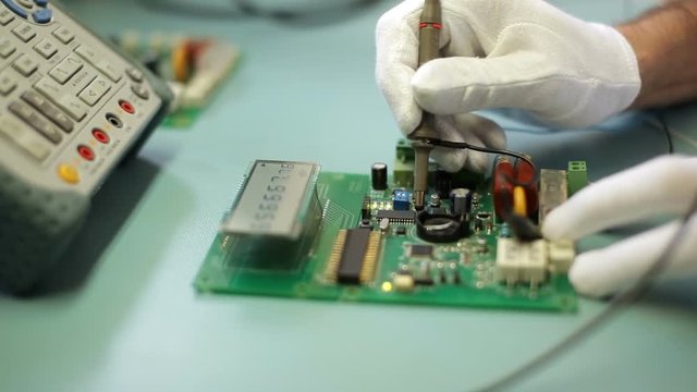 Electronics engineer configure the device, measuring of electric signals with oscilloscope on dielectric table.