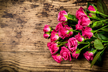 Bouquet of little pink roses on wooden background