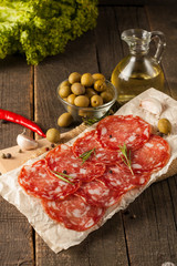 Chorizo sausage and salami, thin cut. spanish salami on the wood background with spices, paprika, pepper. Spicy food. Chili.