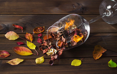Autumn leaves in a wine glass on wooden table background