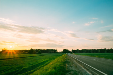 Fototapeta na wymiar Sunset on a background of green fields and roads