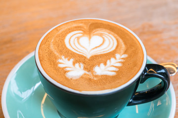 A Cup of hot latte art coffee on wooden table
