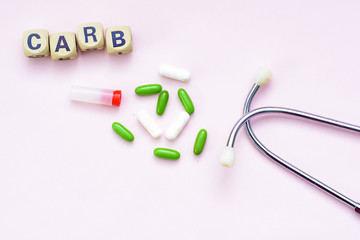 Pink background inscription carb, pills and stethoscope