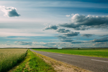 Fototapeta premium Cloudy sky over the green fields and the highway