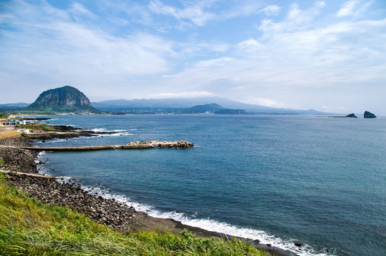View of a ocean, coastline and a Daejeong-eup town from the Songaksan Mountain on Jeju Island in South Korea. Sanbangsan Mountain is in the background.