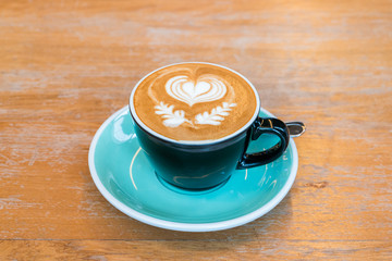 A Cup of hot latte art coffee on wooden table
