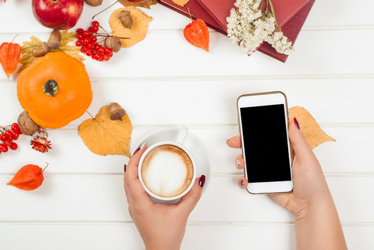 Coffee break, using cell phone. Top view of autumn background.