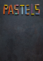  Text "Pastels" created with oil pastels on slate