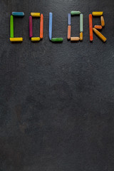 Text "Color" created with oil pastels on slate