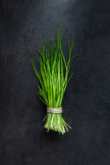 Bunch of fresh green chives on gray slate