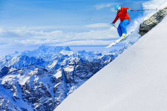 Man jumping from the rock, skiing on fresh powder snow with swis