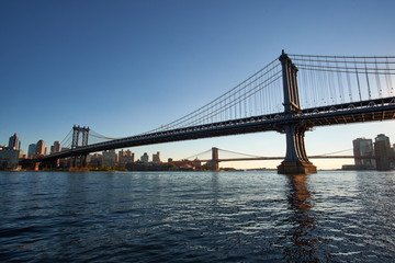 Naklejka premium Manhattan Bridge seen from the north from the Manhattan side in a very low orange sunlight with Brooklyn Bridge in the background