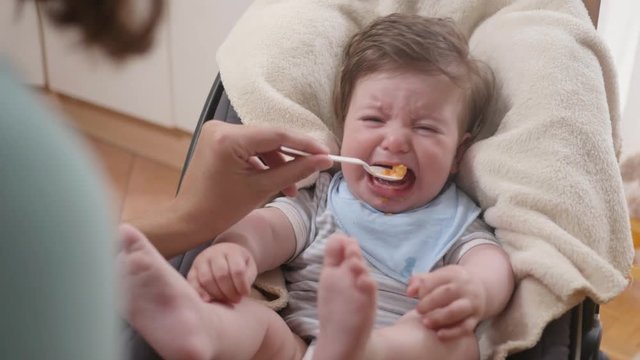 POV shot of a hungry baby being fed with baby food by his mother.
