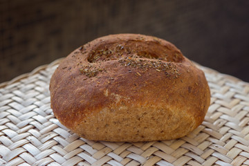 Loaf of rye bread homemade with herbs. one whole loaf of fresh bread lies on a wicker table.