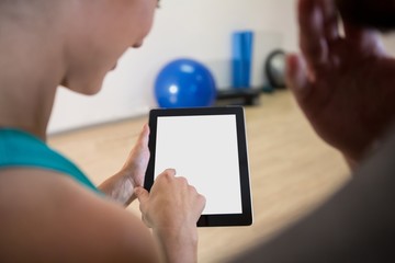Woman showing digital tablet to fitness trainer