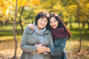 Portrait of smiling caucasian senior mother with her adult daughter hugging and looking at the...