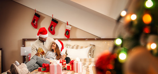 Happy couple making a toast on the bed during Christmas holidays.