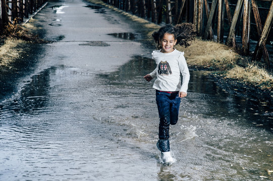 girl playing outdoors with puddle