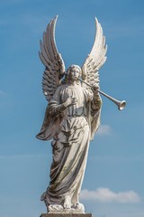 Fototapeta premium White herald angel statue on a blue sky with a few clouds