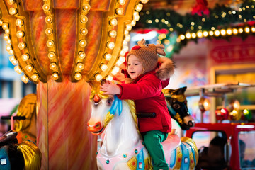 Child riding carousel on Christmas market - obrazy, fototapety, plakaty