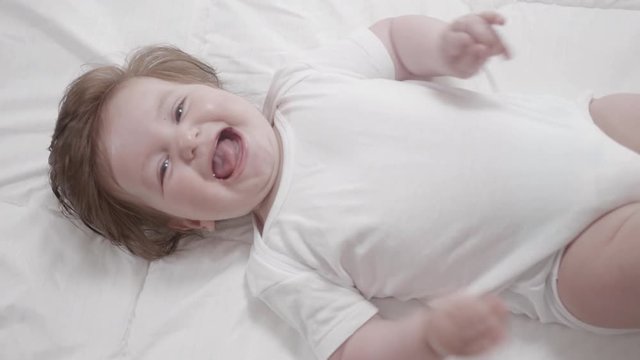 POV shot of a cute smiling baby lying down on his bed.
