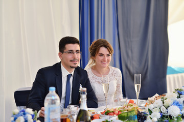 Beautiful wedding couple in restaurant. White decor for bride and groom. Colorful decoration for celebration. Beauty bridal interior for marriage. Bouquet, food and flowers in hall